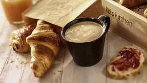 A wooden tray with croissants, a cup of coffee, and a half-eaten piece of bread with jam. - ibis Reims Tinqueux (Tinqueux)