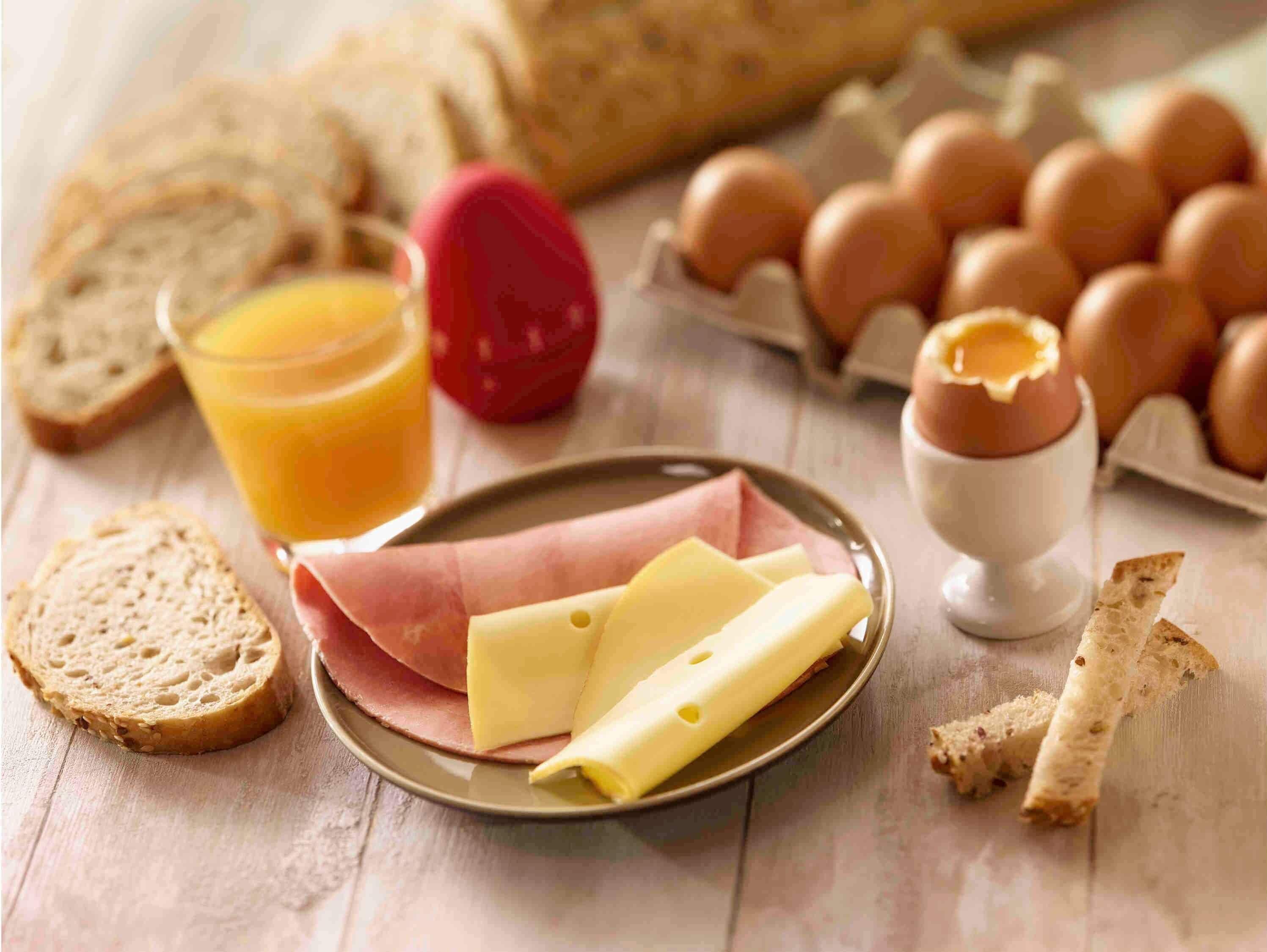 A breakfast setting with bread, eggs, cheese, and a glass of orange juice.