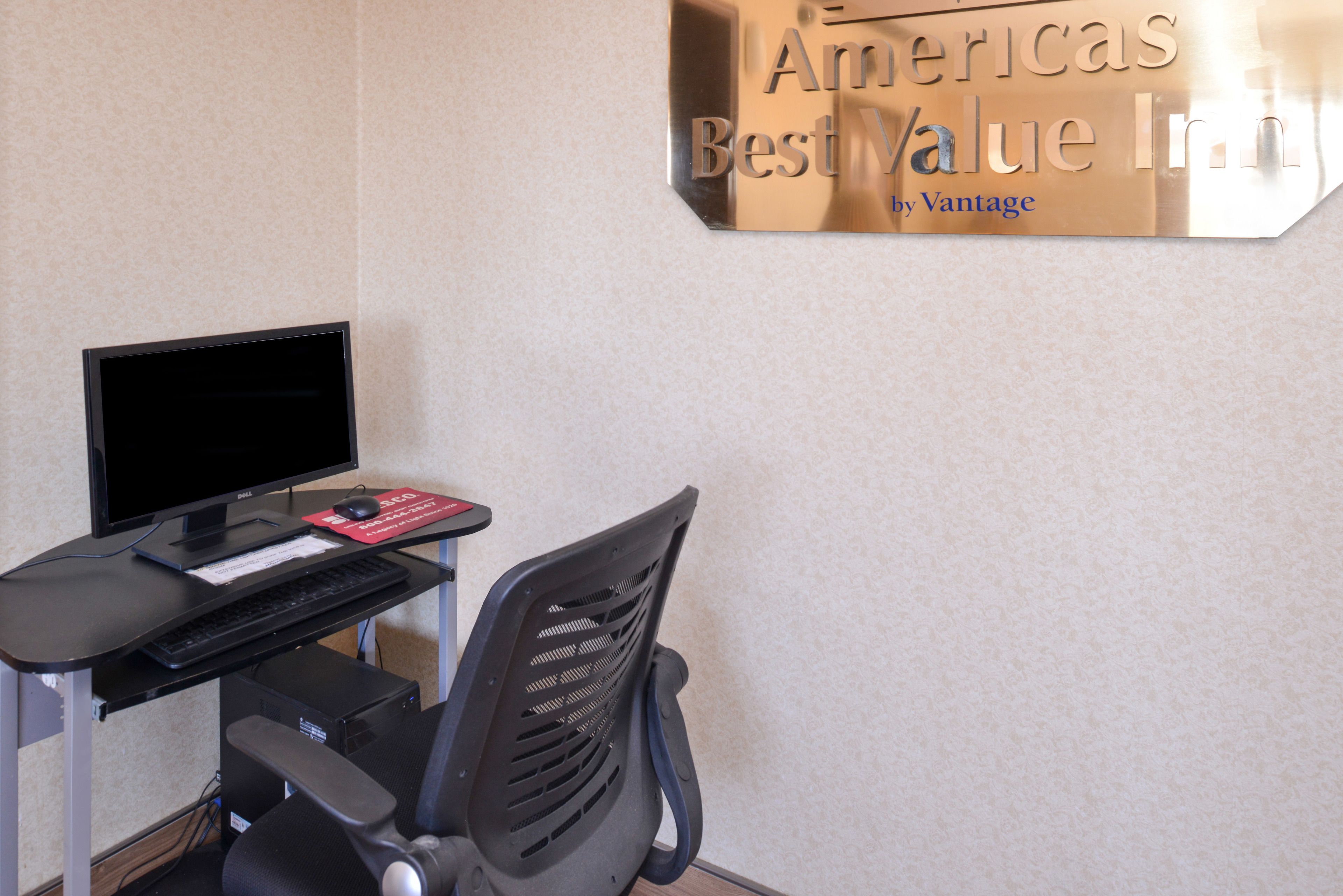 A computer desk with a monitor, keyboard, and mouse, and a chair with a backrest.