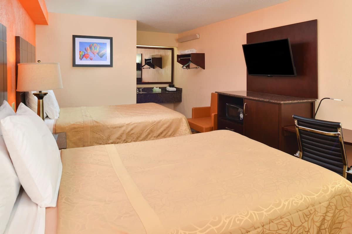 Een hotelkamer met twee bedden, een televisie, een bureau en een stoel.