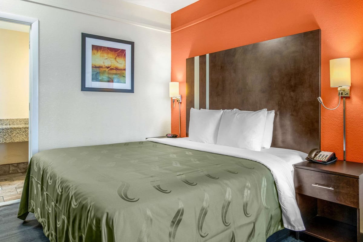 Une chambre d’hôtel avec un lit, une table de chevet et un tableau au mur.