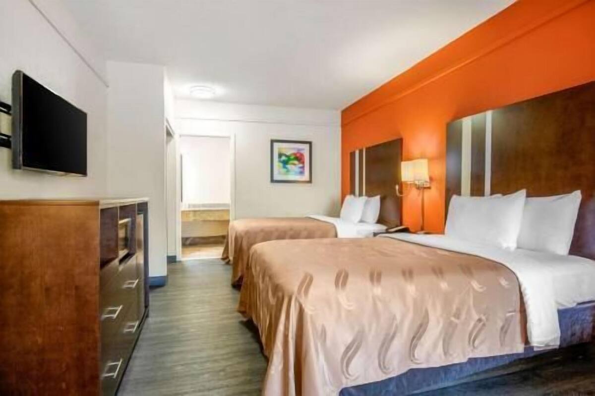 Une chambre d’hôtel avec deux lits, une télévision, un bureau et un tableau au mur.