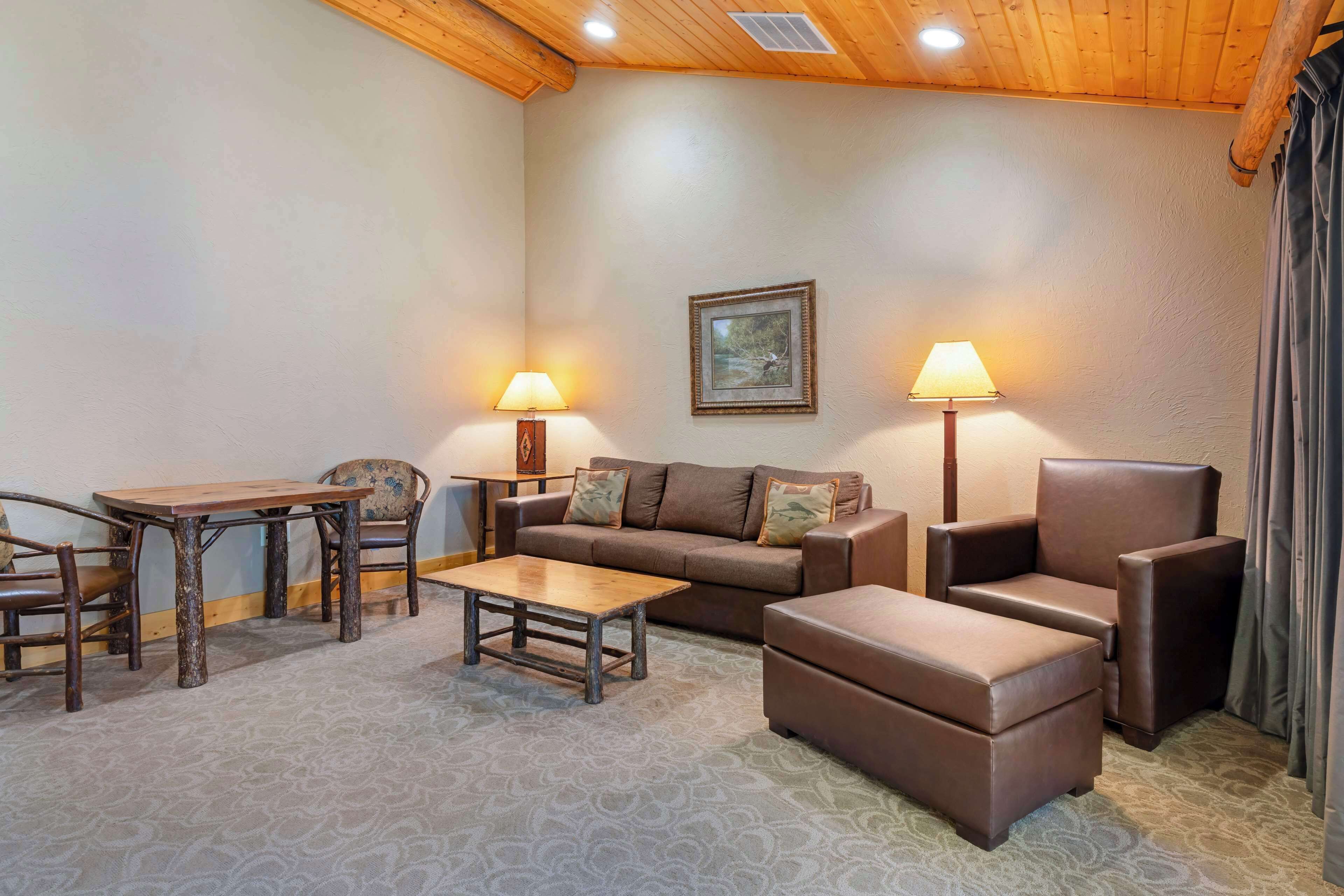 A cozy living room with a wooden ceiling, a sofa, a coffee table, and two lamps.