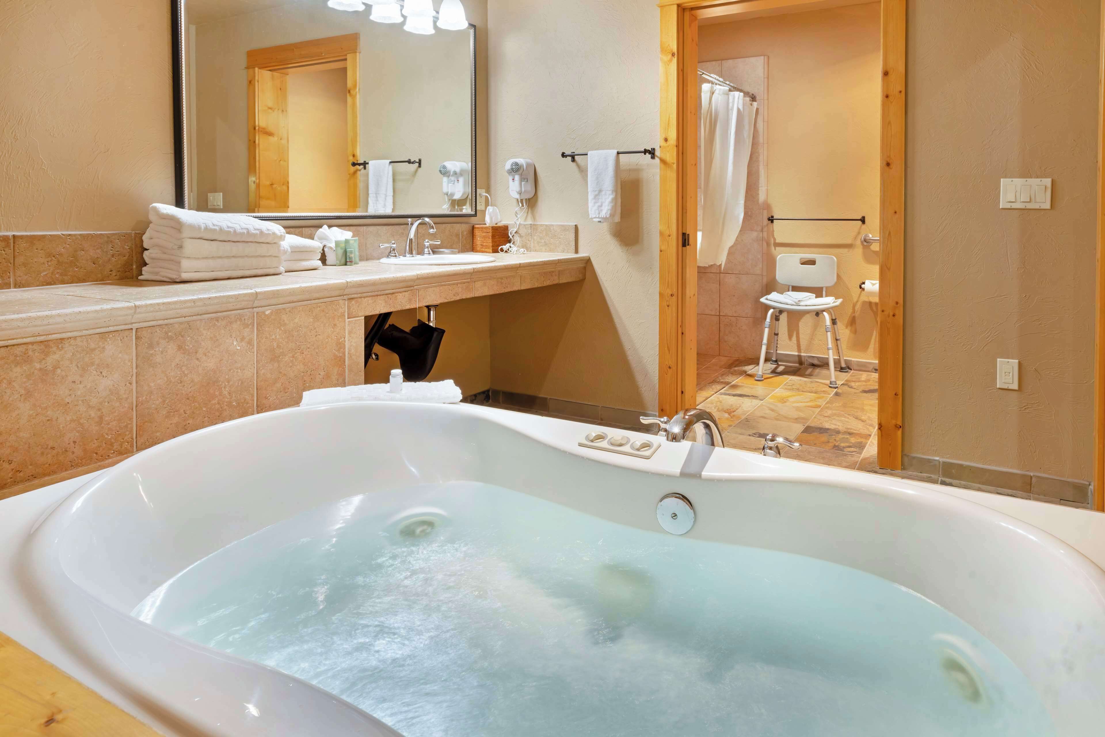A modern bathroom with a large bathtub, a sink, a mirror, and a shower area.