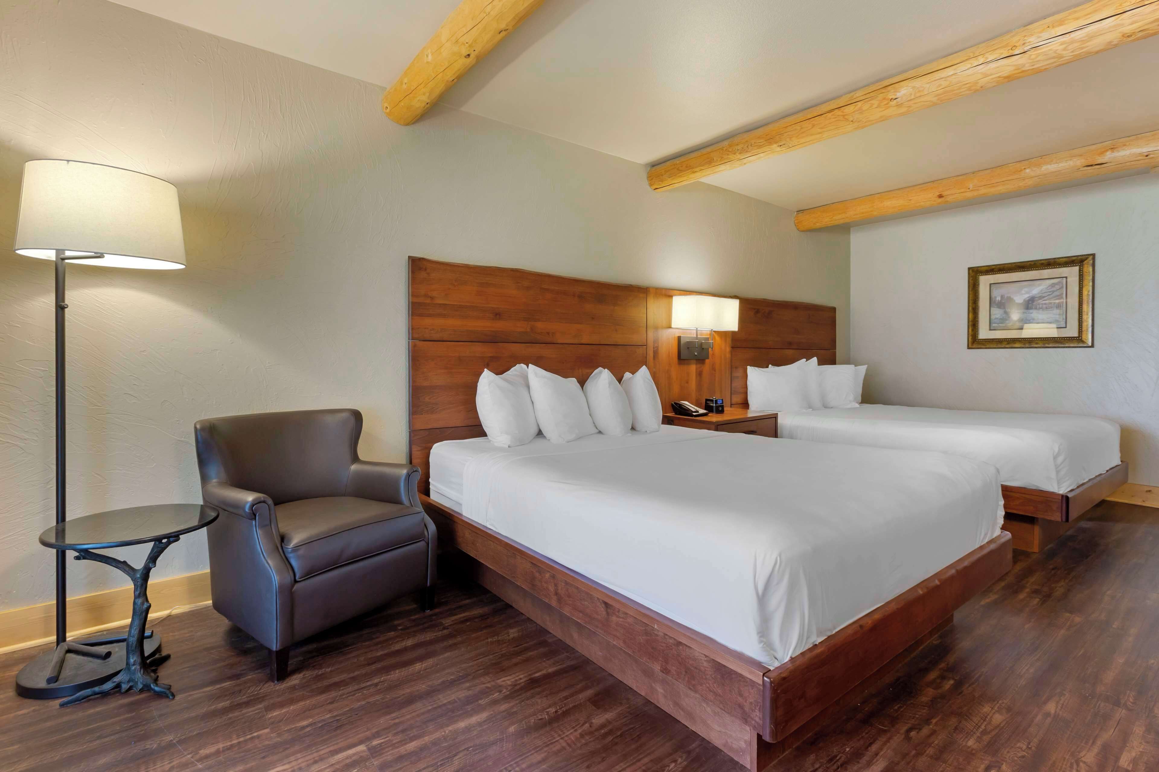 Une chambre d’hôtel avec un grand lit, une chaise, une petite table et une lampe.