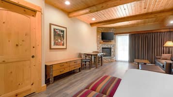 Una habitación acogedora con techo de madera, chimenea, televisor y cama con almohadas a rayas.