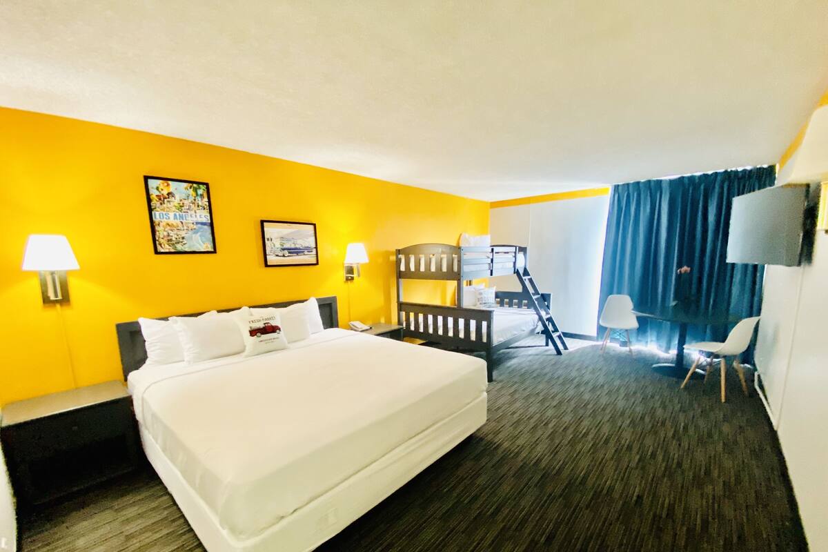 Una habitación de hotel con una cama grande, una litera, un escritorio y una silla.
