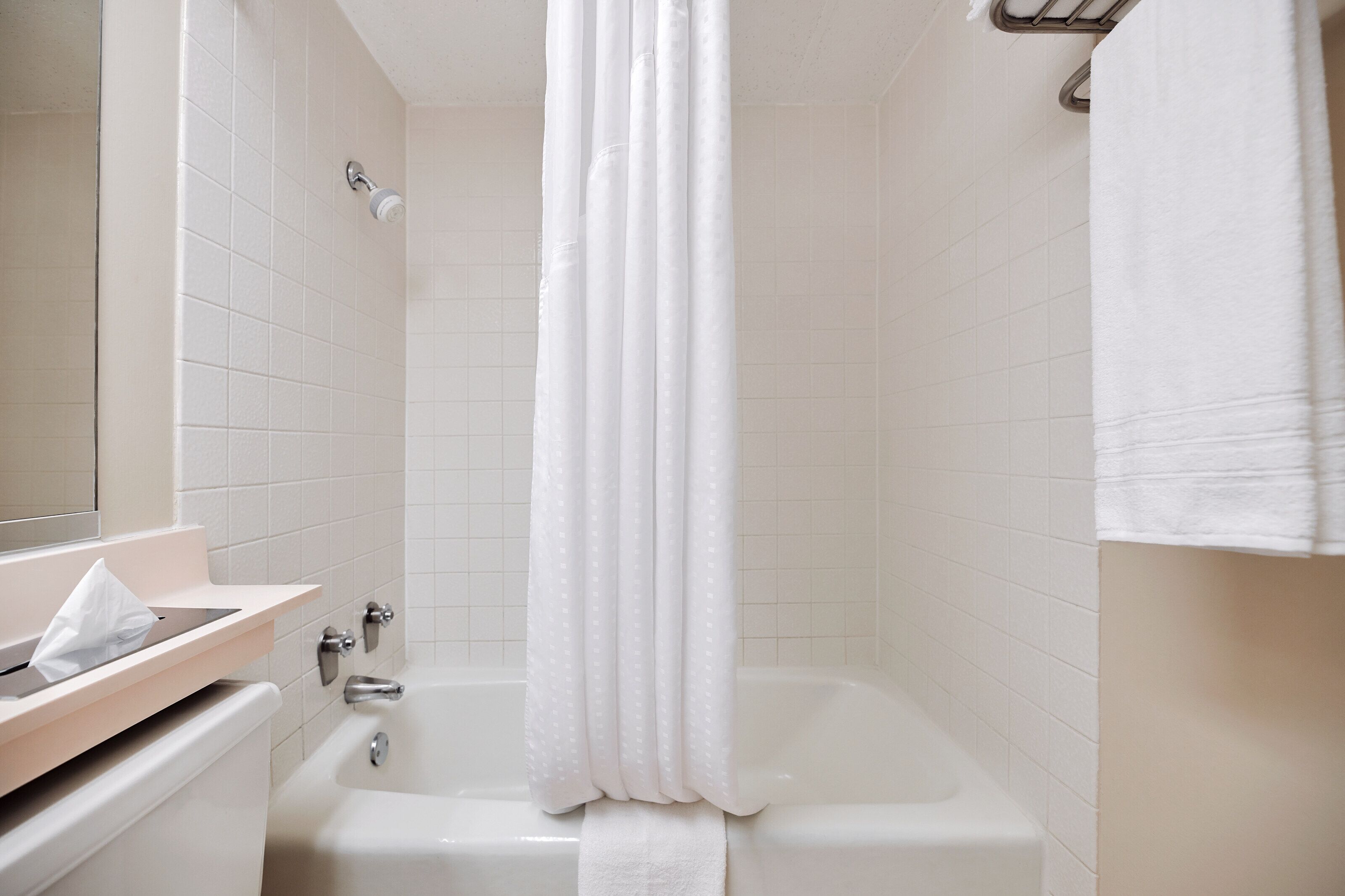 A bathroom with a bathtub, a towel rack, and a mirror.