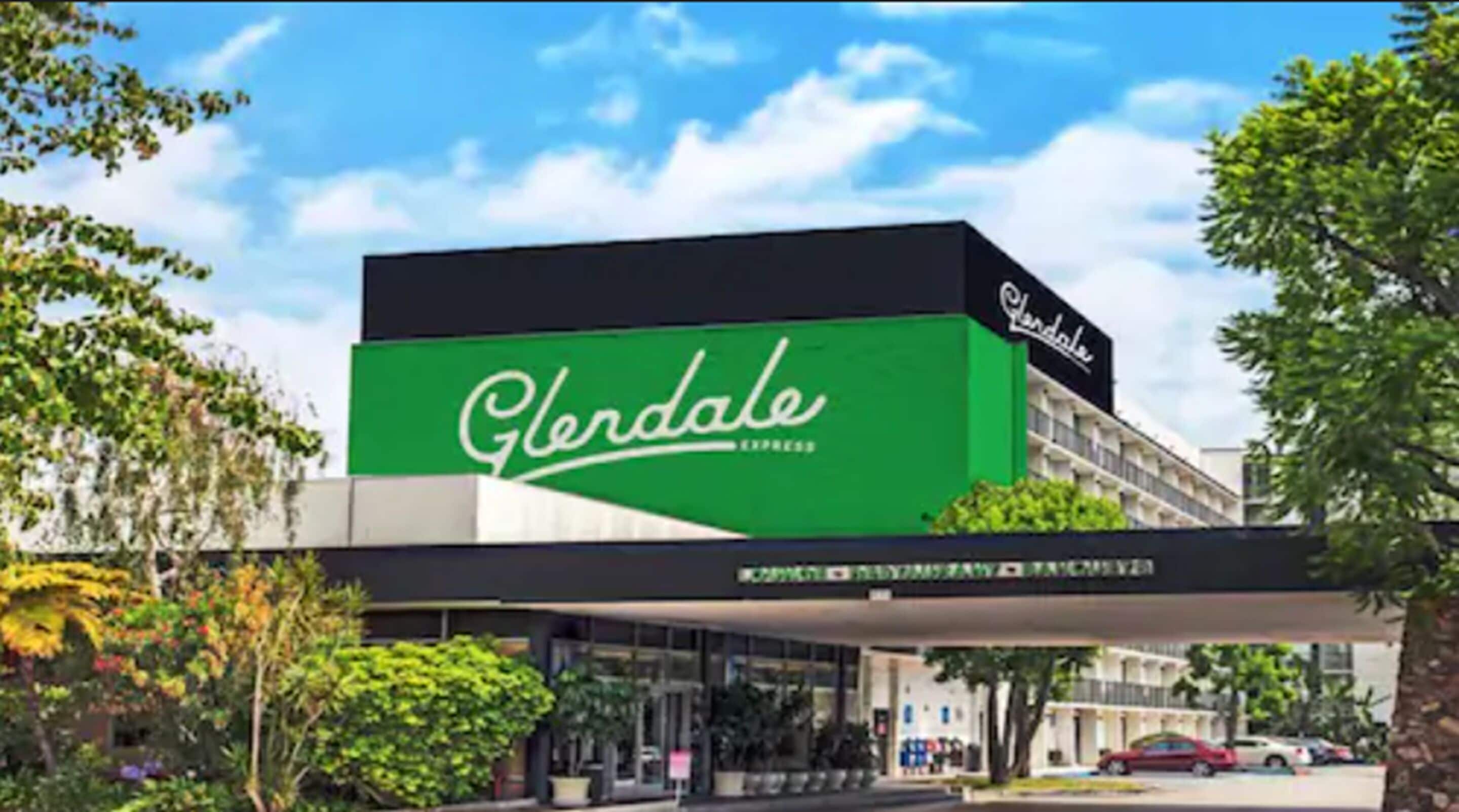 Een hotel genaamd 'Glendale Express' met een opvallend groen bord, moderne architectuur en een overdekt entreegebied.