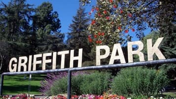 A sign for Griffith Park with a metal fence and colorful flower beds in the foreground.
