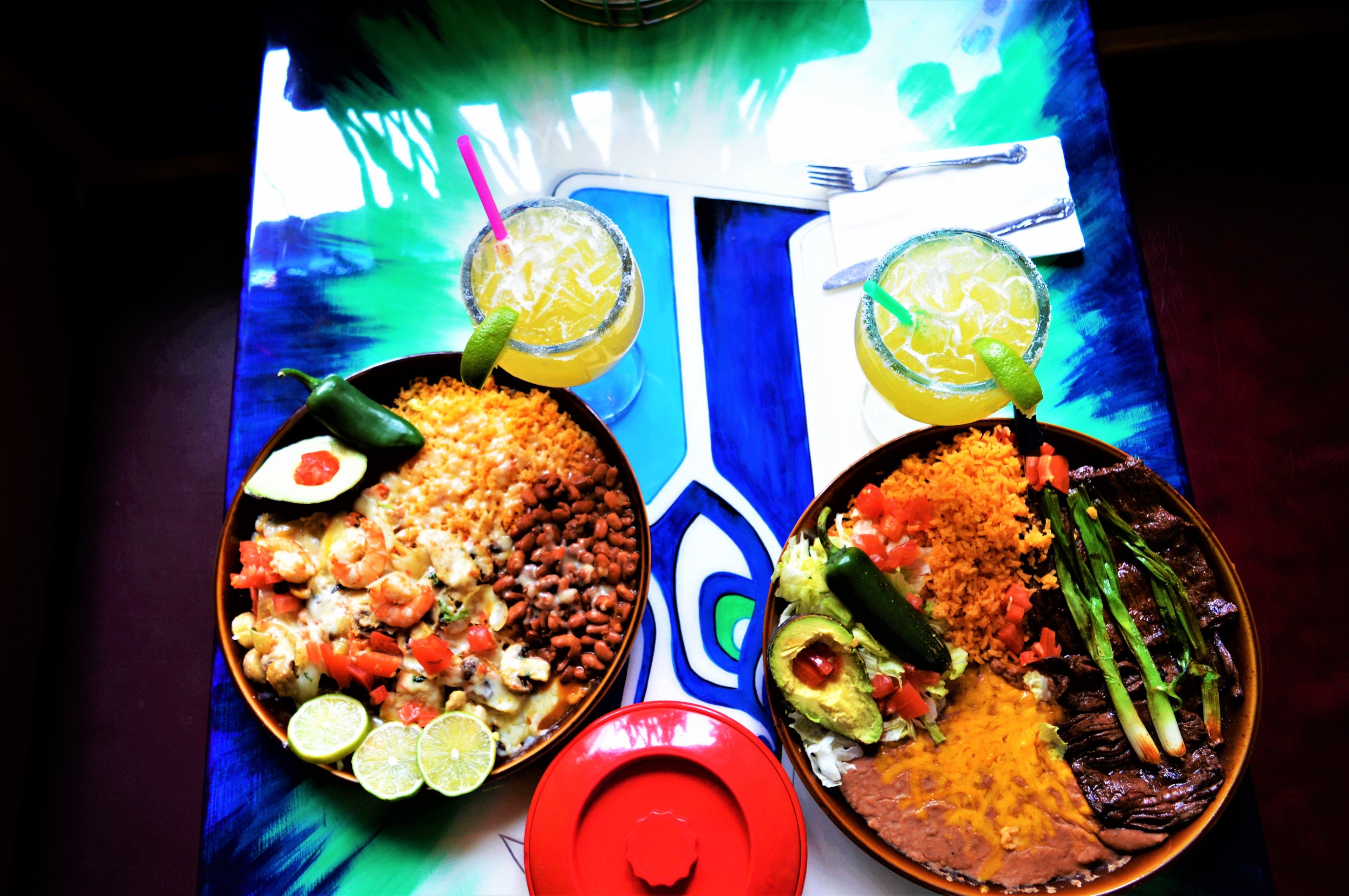 Dos platos de comida con bebidas sobre una mesa.