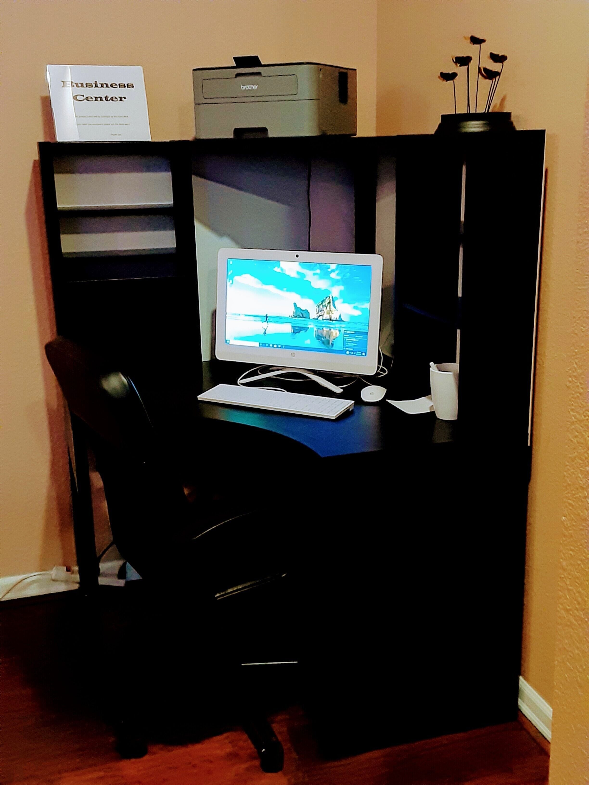 A home office setup with a desktop computer, a printer, and a sign reading "Business Center".