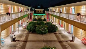 A motel with a central courtyard, multiple balconies, and a row of rooms with doors in various colors. - GuestHouse Enumclaw (Enumclaw)