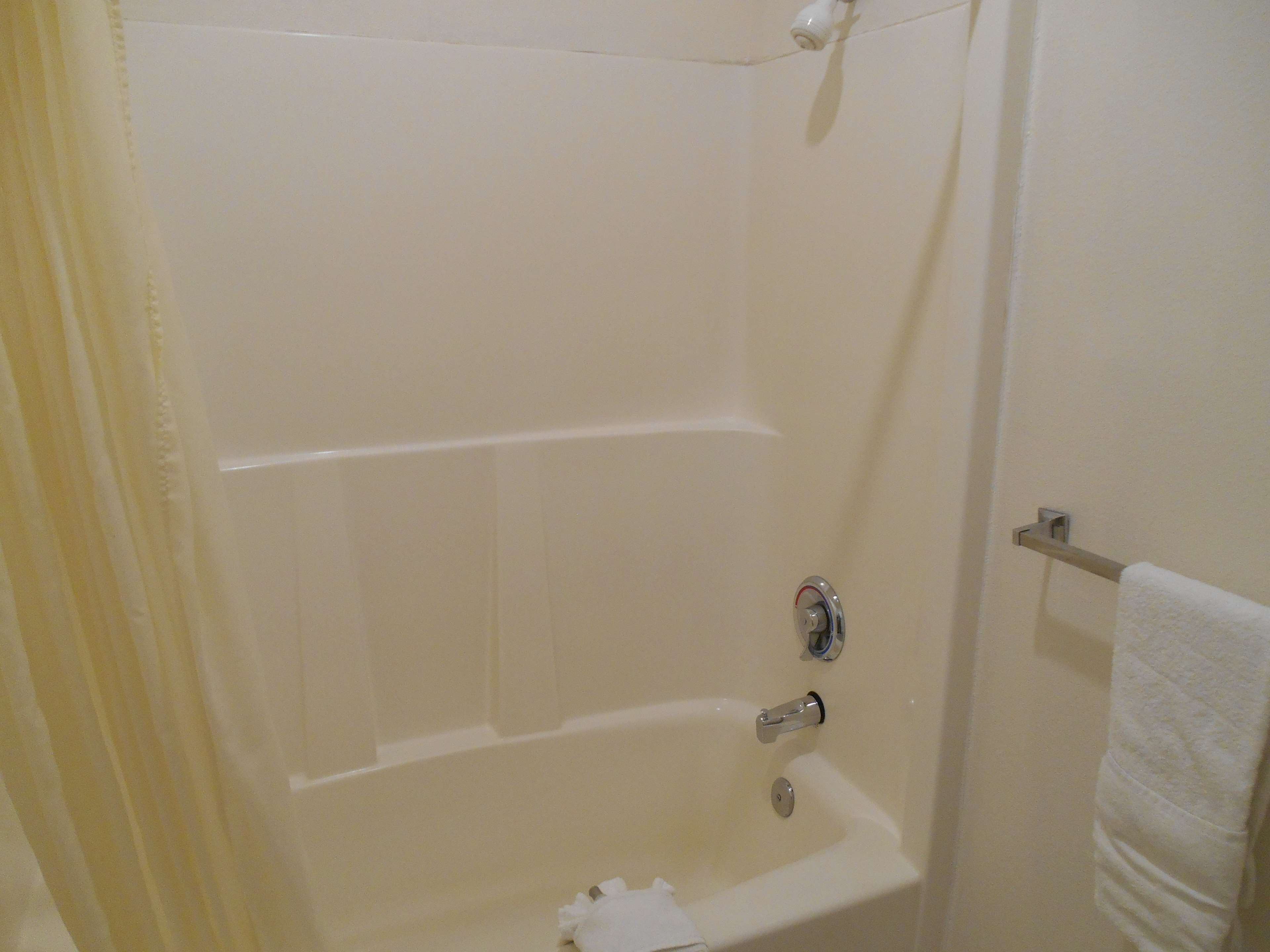 A white bathtub with a showerhead, a towel rack, and a towel hanging on it.