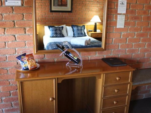 A wooden desk with a bottle of wine, a bag of chips, and a smartphone.