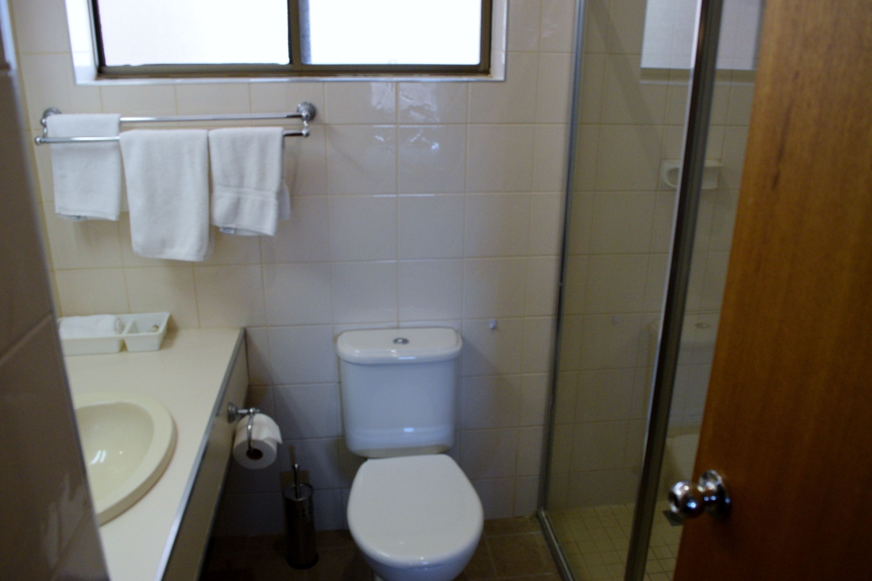 A bathroom with a toilet, sink, and a window above the sink.