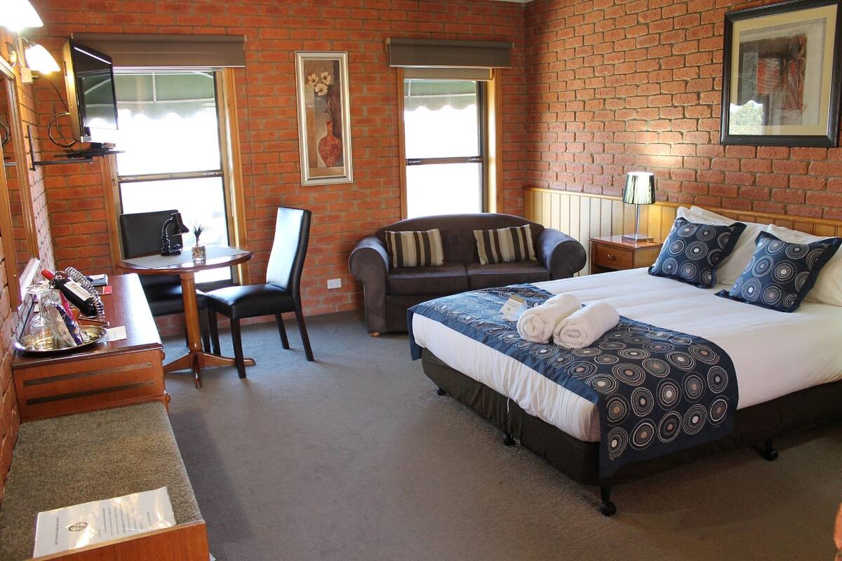 A hotel room with a bed, a desk, a chair, and a sofa.