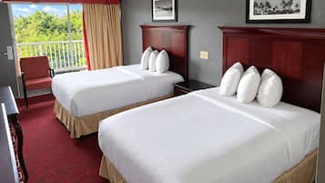 Een hotelkamer met twee bedden, een stoel, een bureau en een balkon met gordijnen.