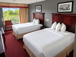 A hotel room with two beds, a chair, a desk, and a balcony with curtains. - Budget Inn (Pompano Beach)