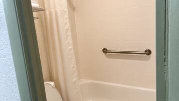 A bathroom with a toilet, a bathtub, and a shower curtain.