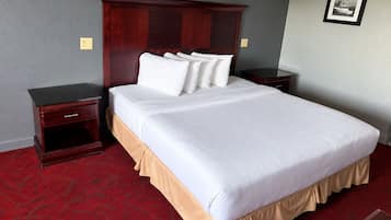 A hotel room with a large bed, two nightstands, a wooden headboard, and a red carpet.