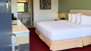 Een hotelkamer met een bed, een bureau, een stoel, een telefoon, een lamp en een kunstwerk aan de muur.