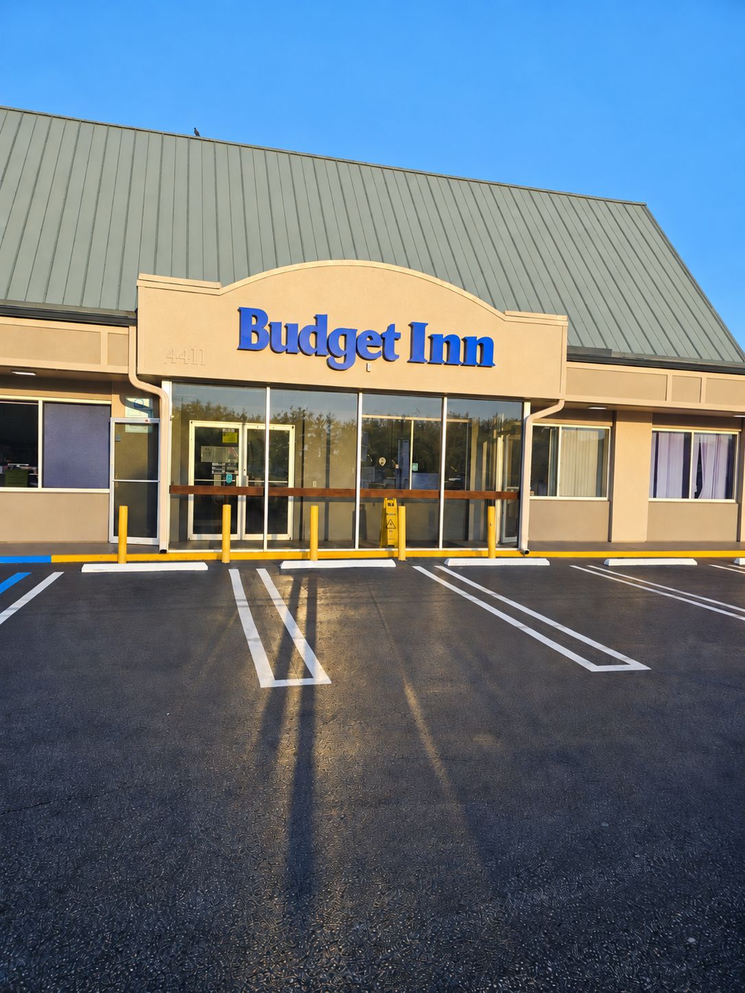Hotel Budget Inn com amplo estacionamento e céu azul.