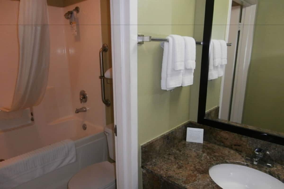 A bathroom with a bathtub, toilet, sink, and a mirror reflecting the room.