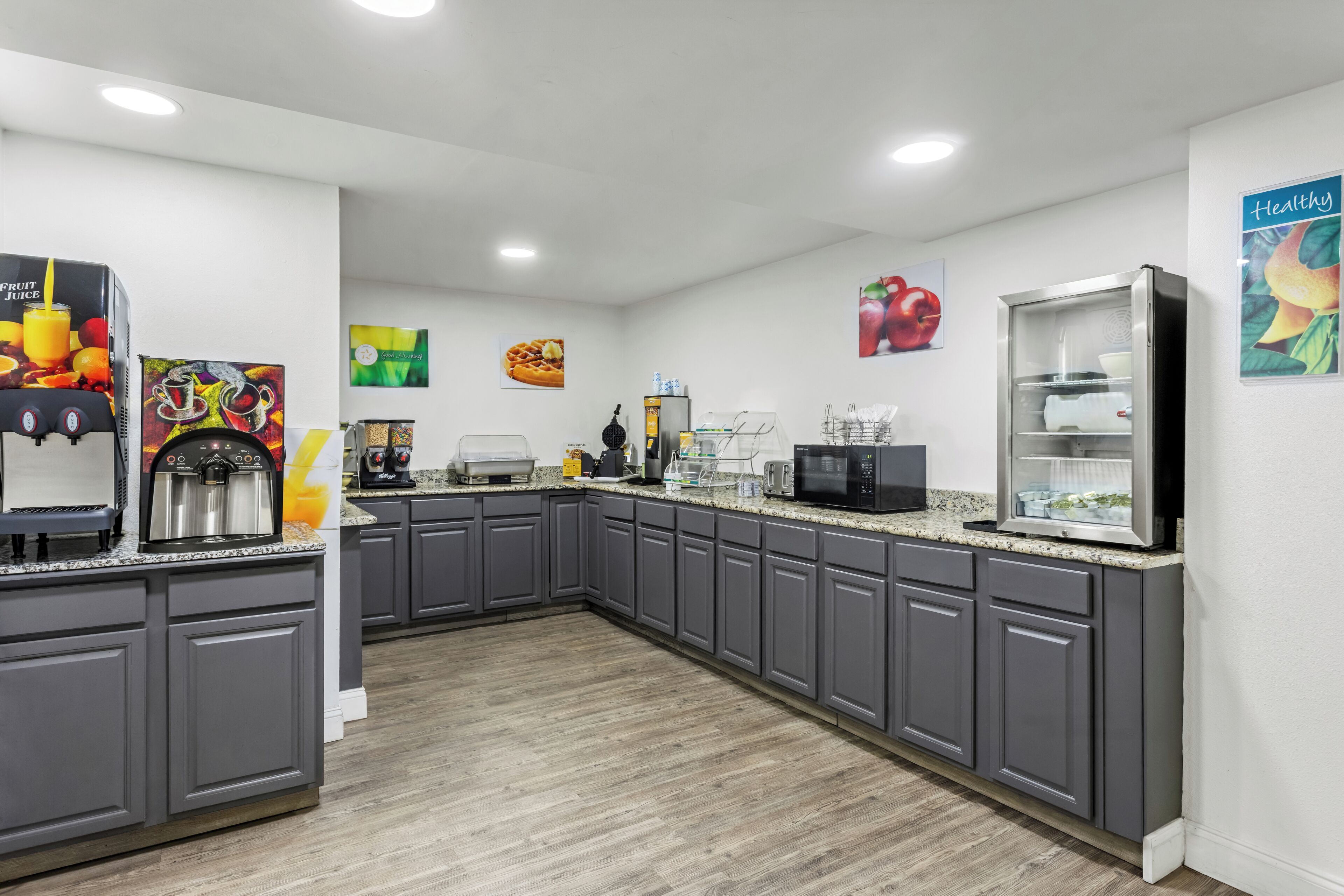 A modern kitchen with grey cabinets, a coffee machine, a microwave, and a refrigerator.