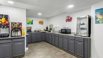 A modern kitchen with grey cabinets, a coffee machine, a microwave, and a refrigerator.