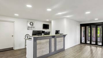 A reception area with a desk, a flat-screen TV, and a sign that reads 'Quality by Choice Hotels.'