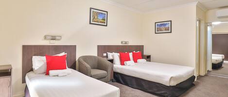 Quarto de hotel com duas camas, uma cadeira e uma pequena mesa.