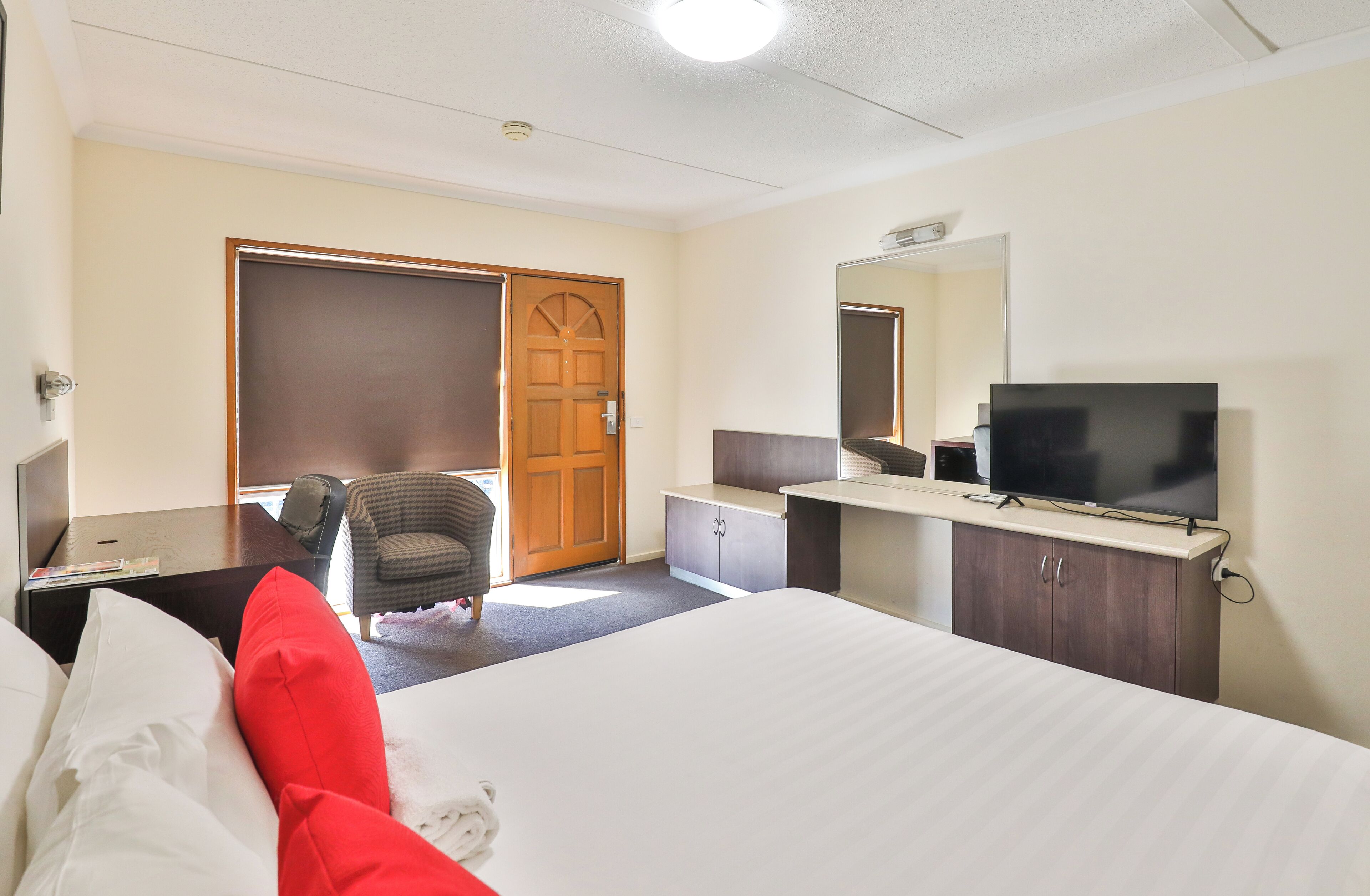 Une chambre d’hôtel comprenant un lit, un bureau avec une chaise, une télévision, une armoire et une porte.