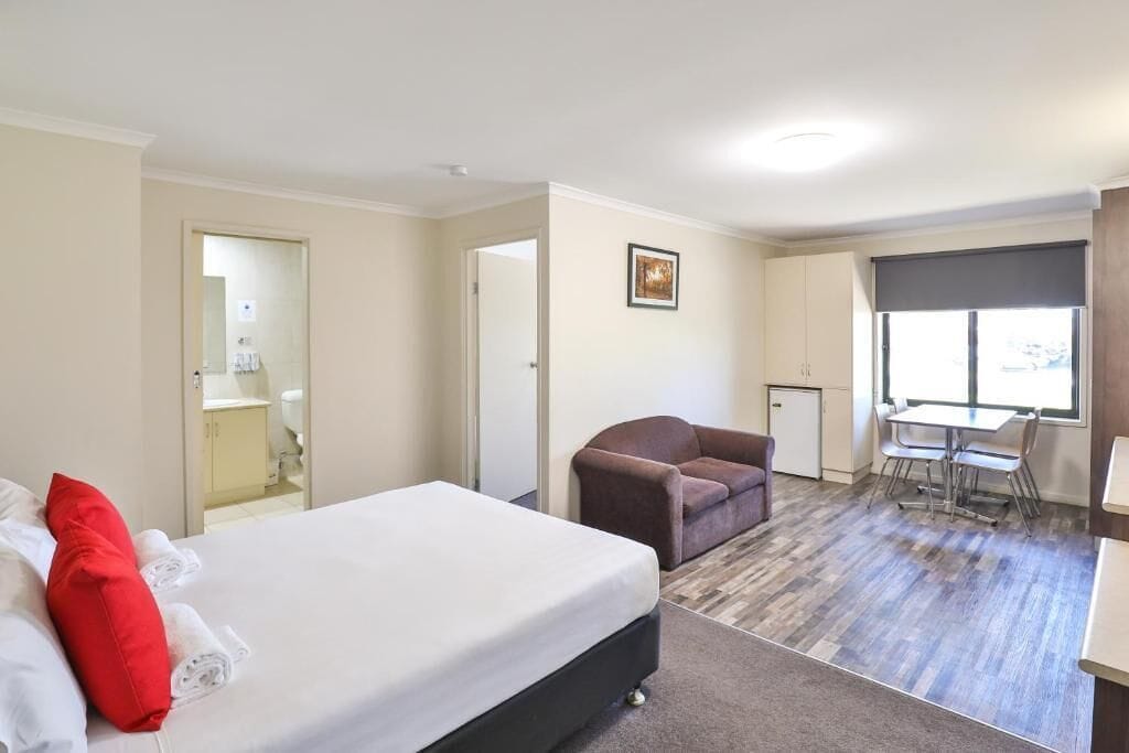 Ein Hotelzimmer mit Bett, Stuhl, kleinem Tisch und Fenster.