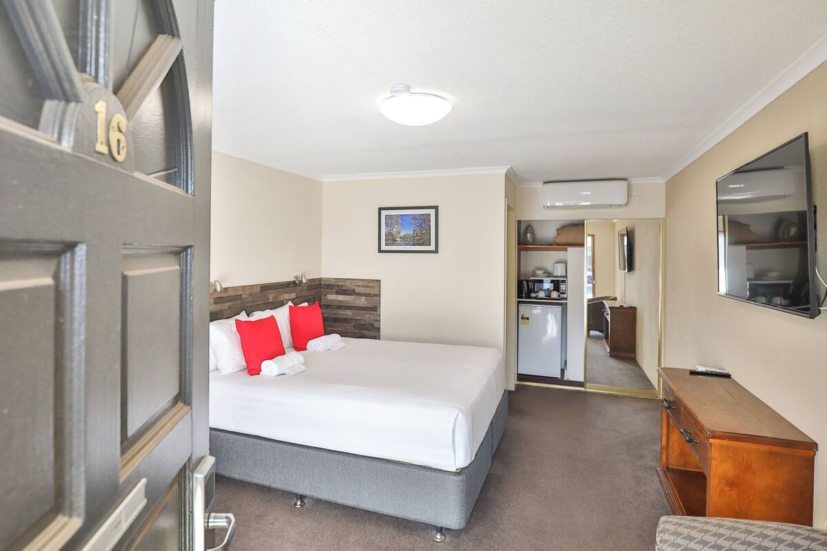 Una habitación de hotel con cama, escritorio, kitchenette y baño.