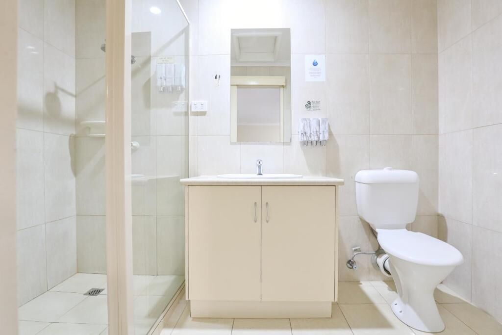 A modern bathroom with a glass-enclosed shower, a white sink with a mirror above, and a toilet.