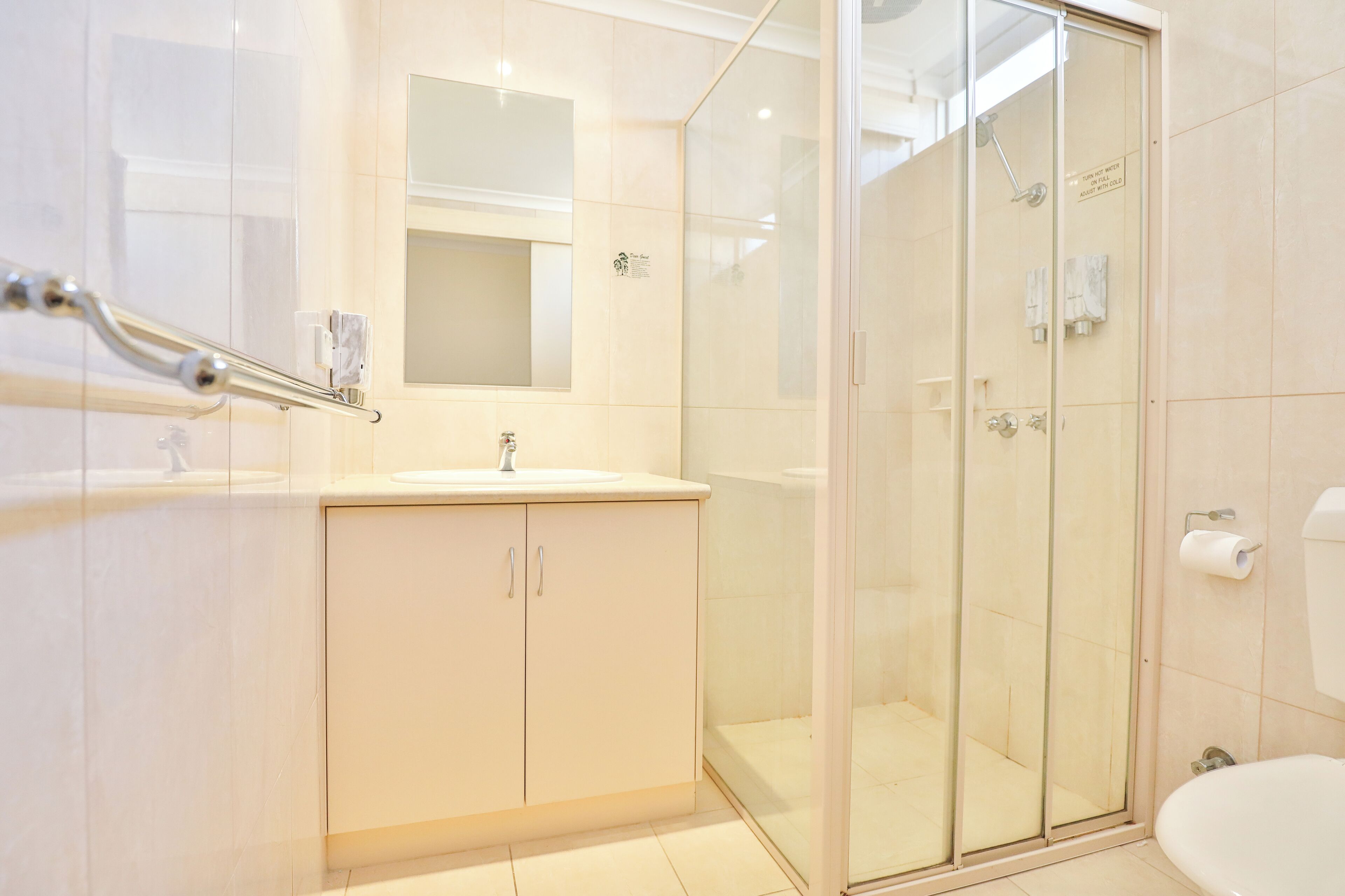 A modern bathroom with a glass-enclosed shower, a white sink, and a mirror above the sink.