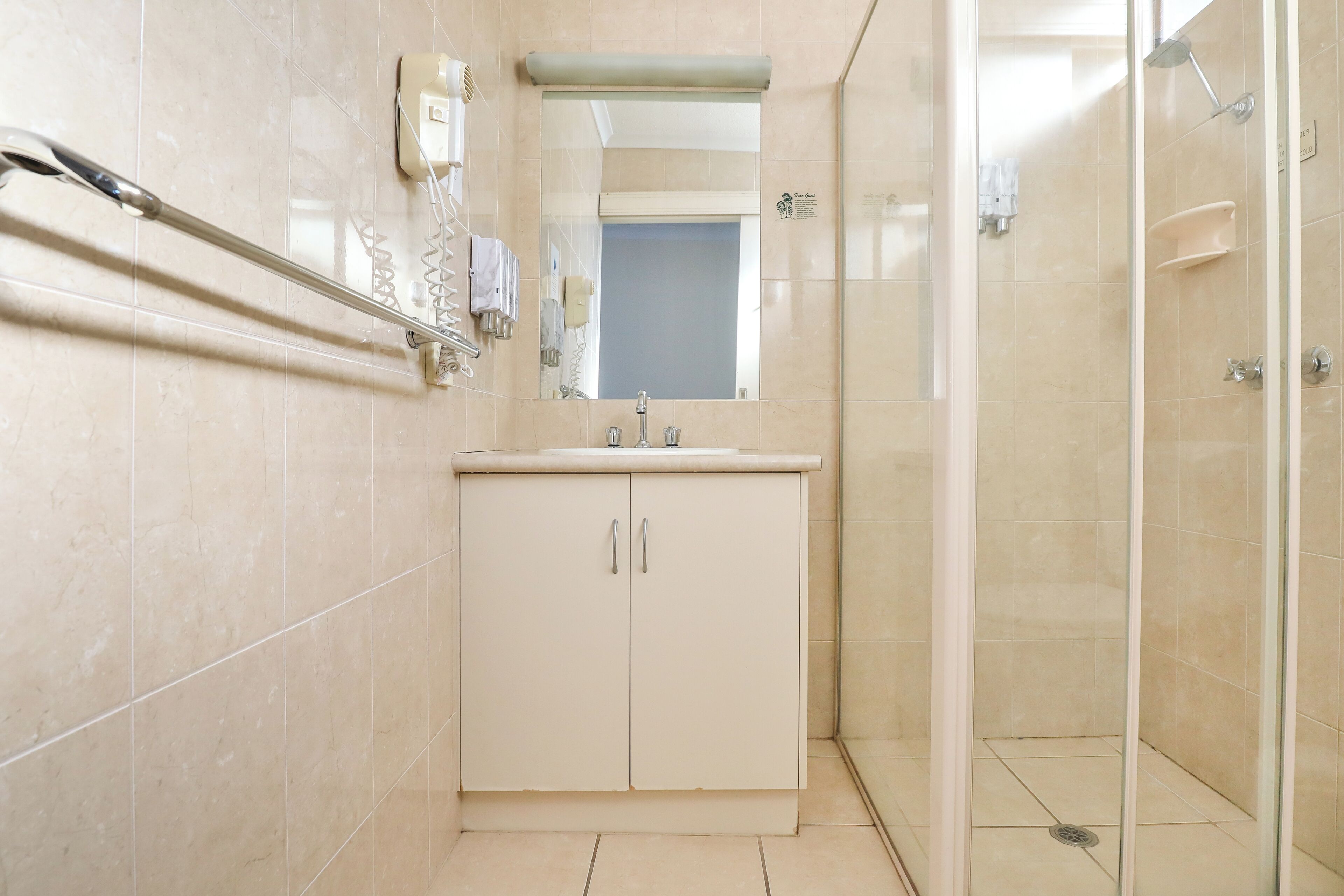 Une salle de bain avec une douche, un lavabo et un miroir.