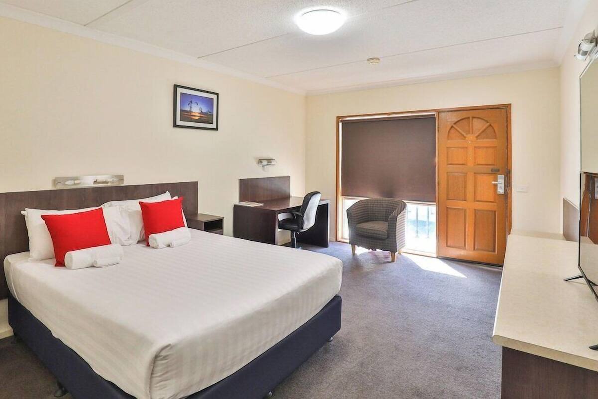 Habitación de hotel con una cama grande, un escritorio, una silla y una puerta.