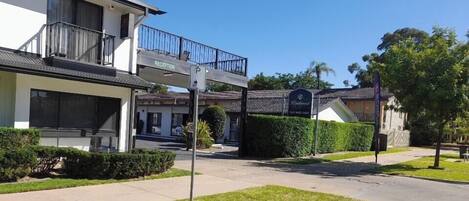 A hotel entrance with a reception desk, a parking sign, and a building labeled "RECEPTION".