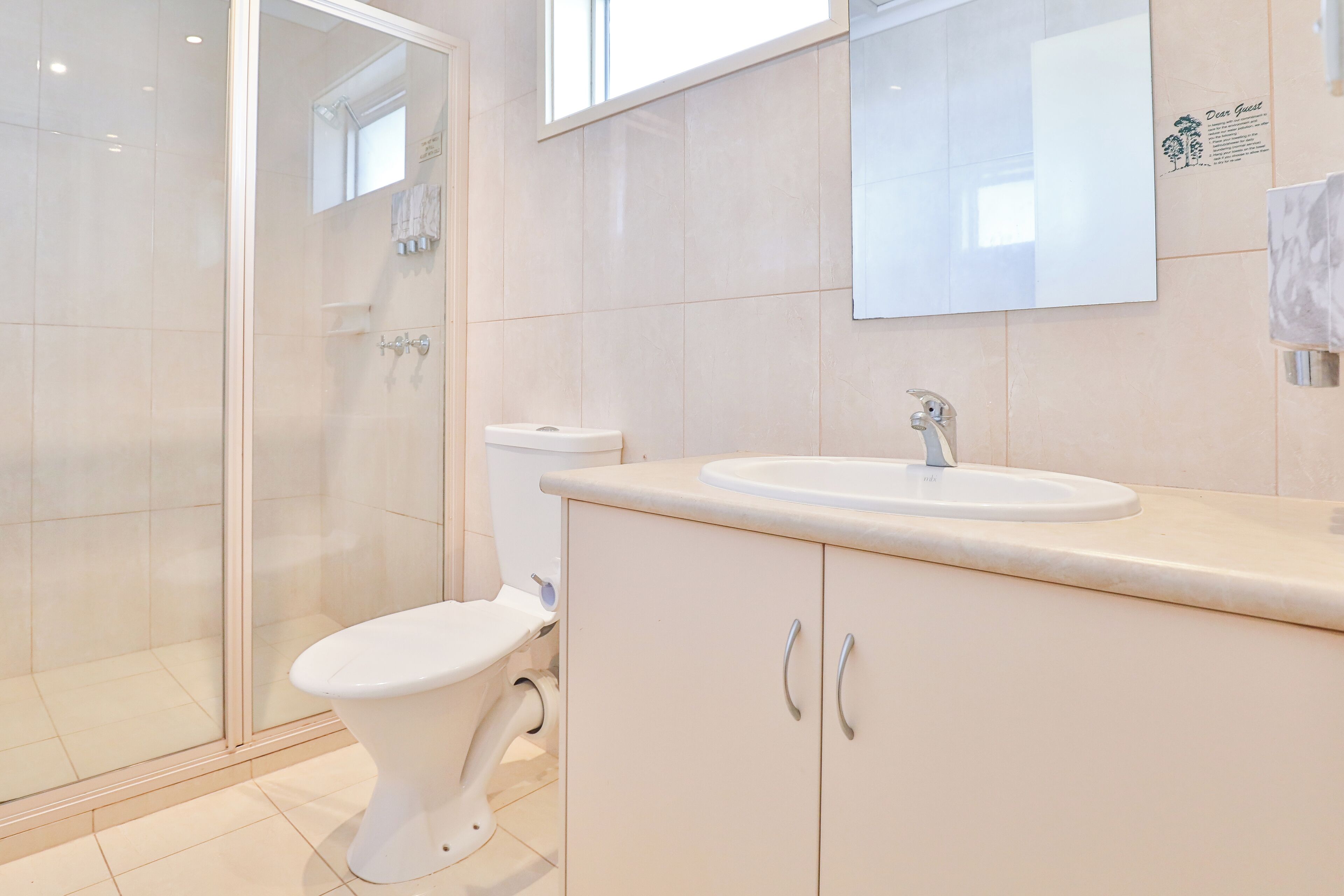 A modern bathroom with a glass shower enclosure, a toilet, and a sink with a mirror above it.