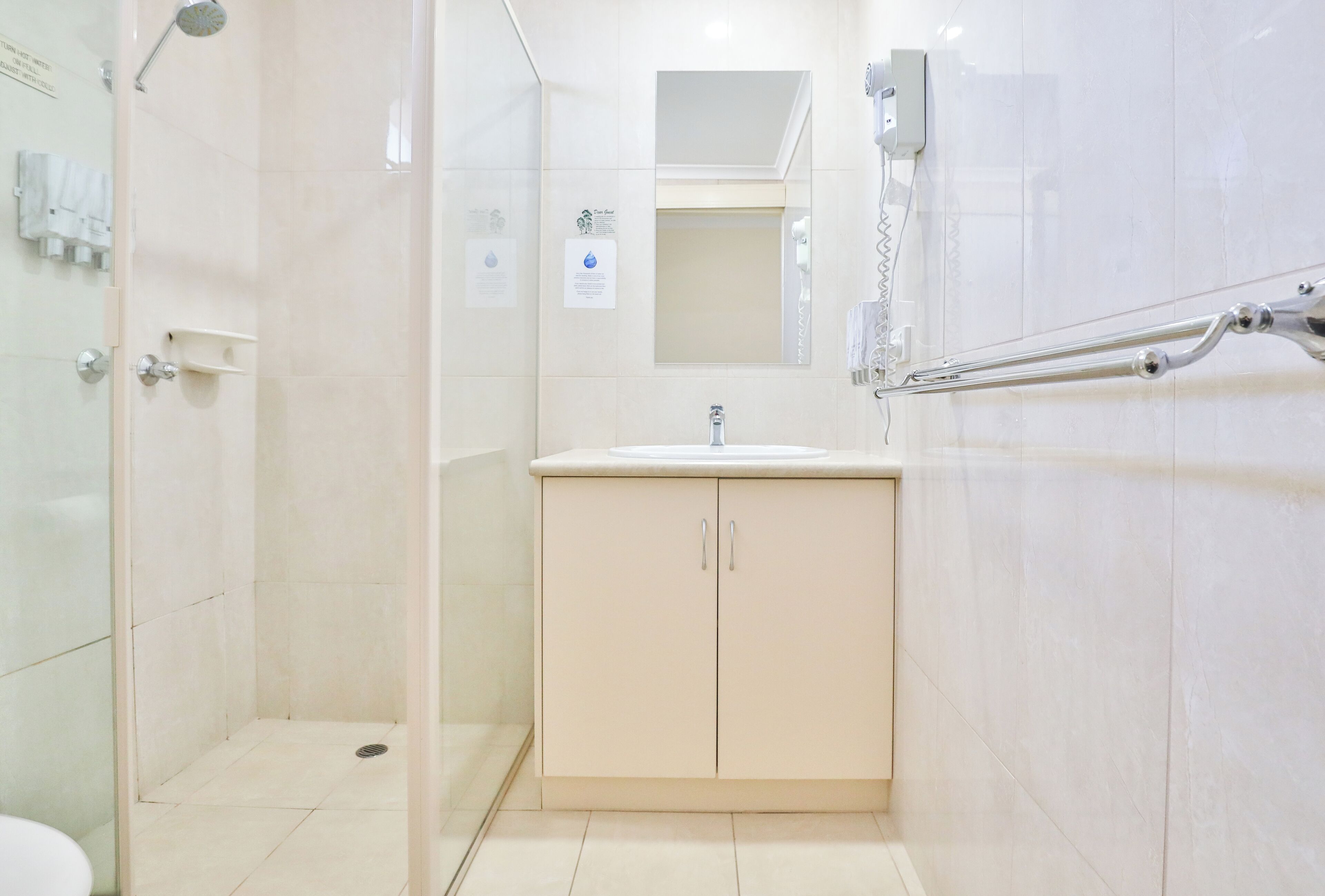 A modern bathroom with a glass-enclosed shower, a sink with a mirror above, and a towel rack.