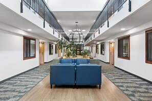 A spacious hotel lobby with a central seating area, a staircase, and a large chandelier. - Best Western Vista Inn At The Airport (Boise)