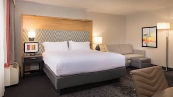 A hotel room with a large bed, a bedside table with a lamp, a chair, and a floor lamp.