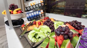 Un bufé con diversas frutas y verduras, entre ellas uvas, fresas y sandía.