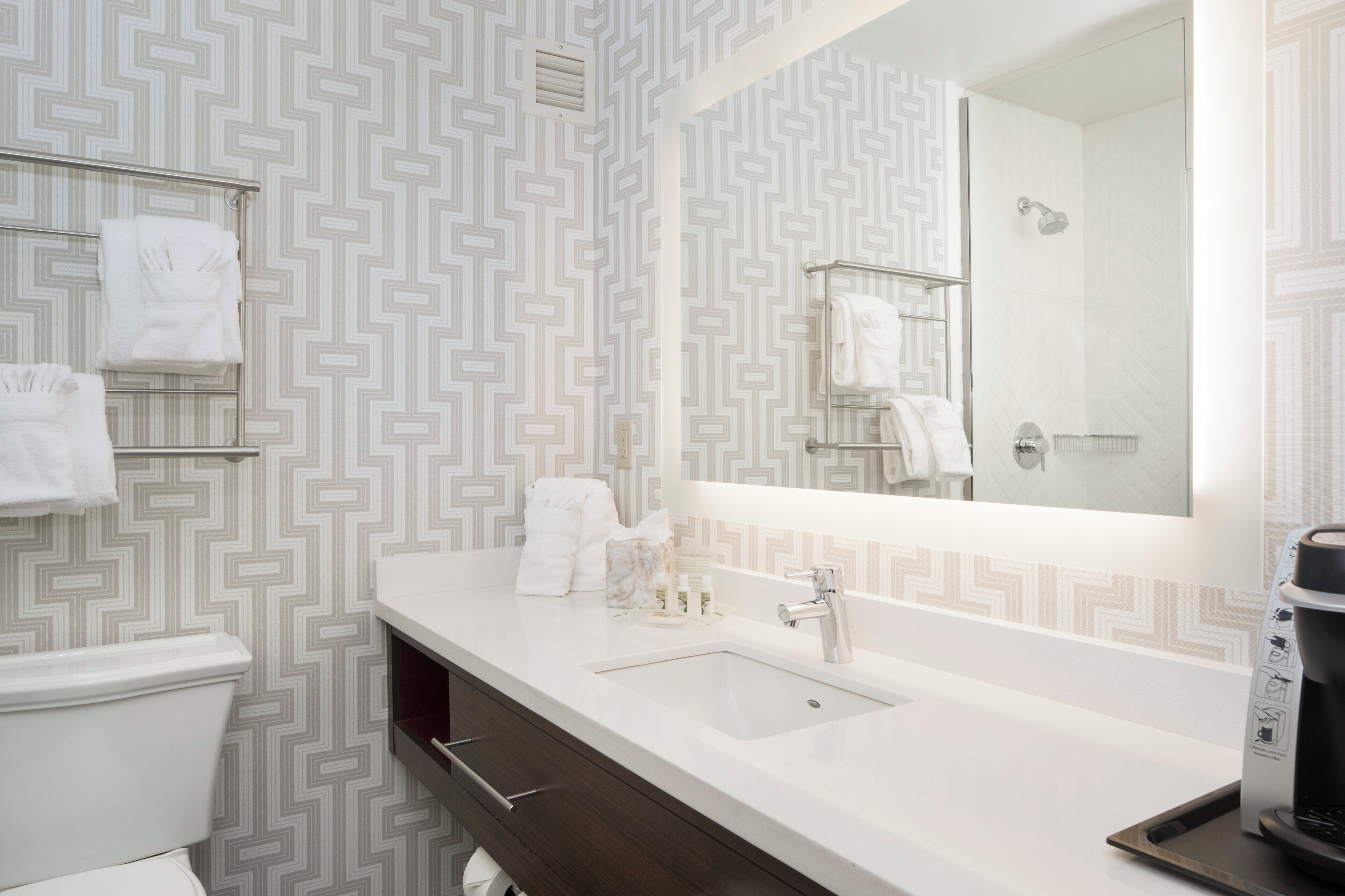 A modern bathroom with a white sink, dark wood vanity, and a large mirror.