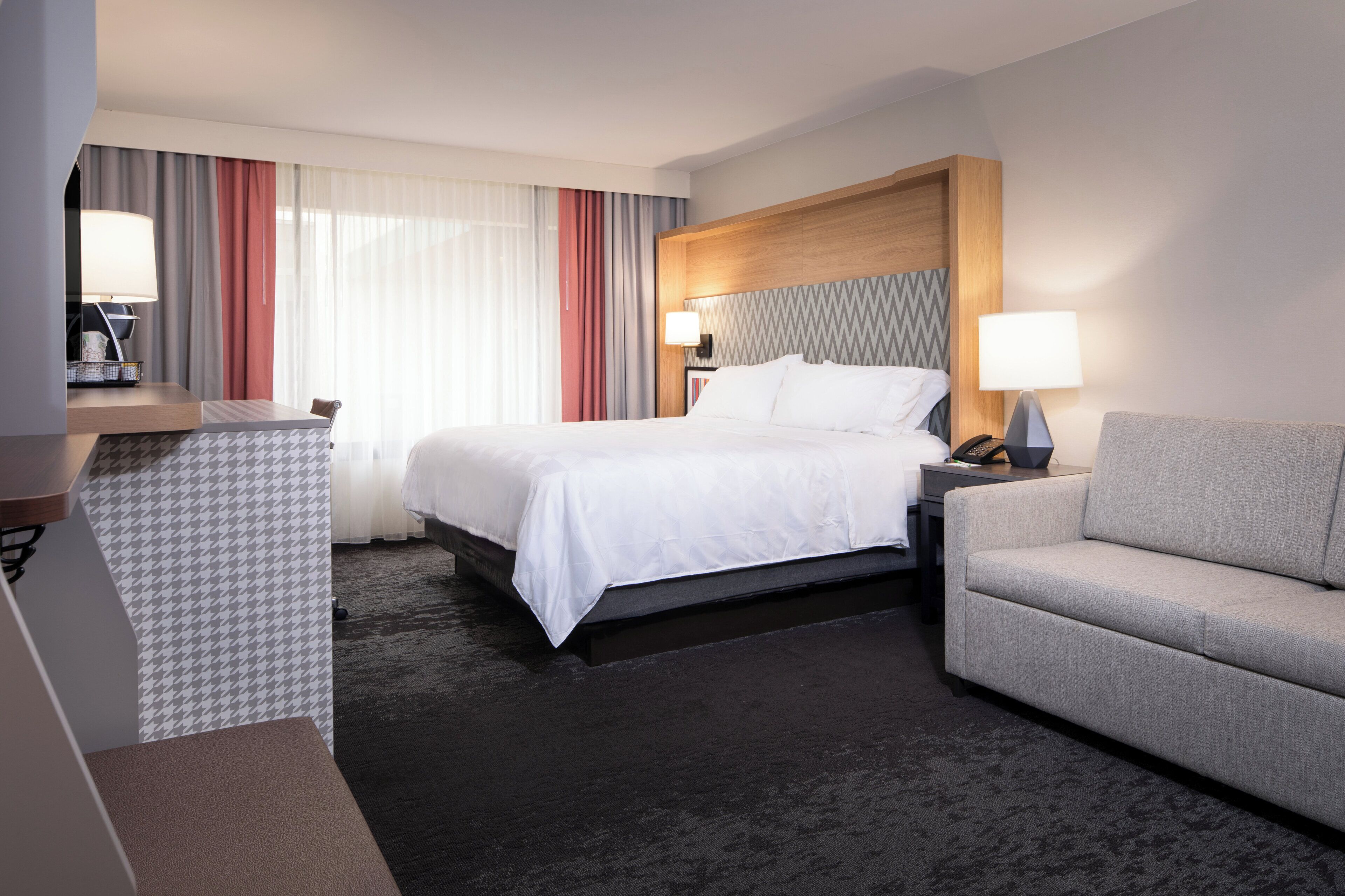 Una habitación de hotel con cama, sofá, escritorio y silla.