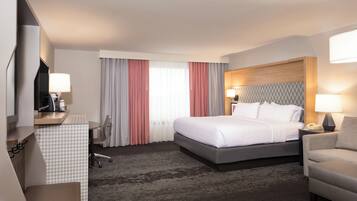 A hotel room with a bed, desk, chair, and a TV.