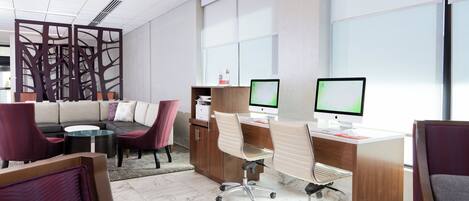 Un espacio de oficina moderno con un sofá, sillas, escritorios y computadoras.