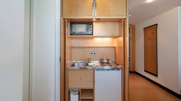 Une petite cuisine équipée d’un four à micro-ondes, d’un évier et d’une cuisinière.